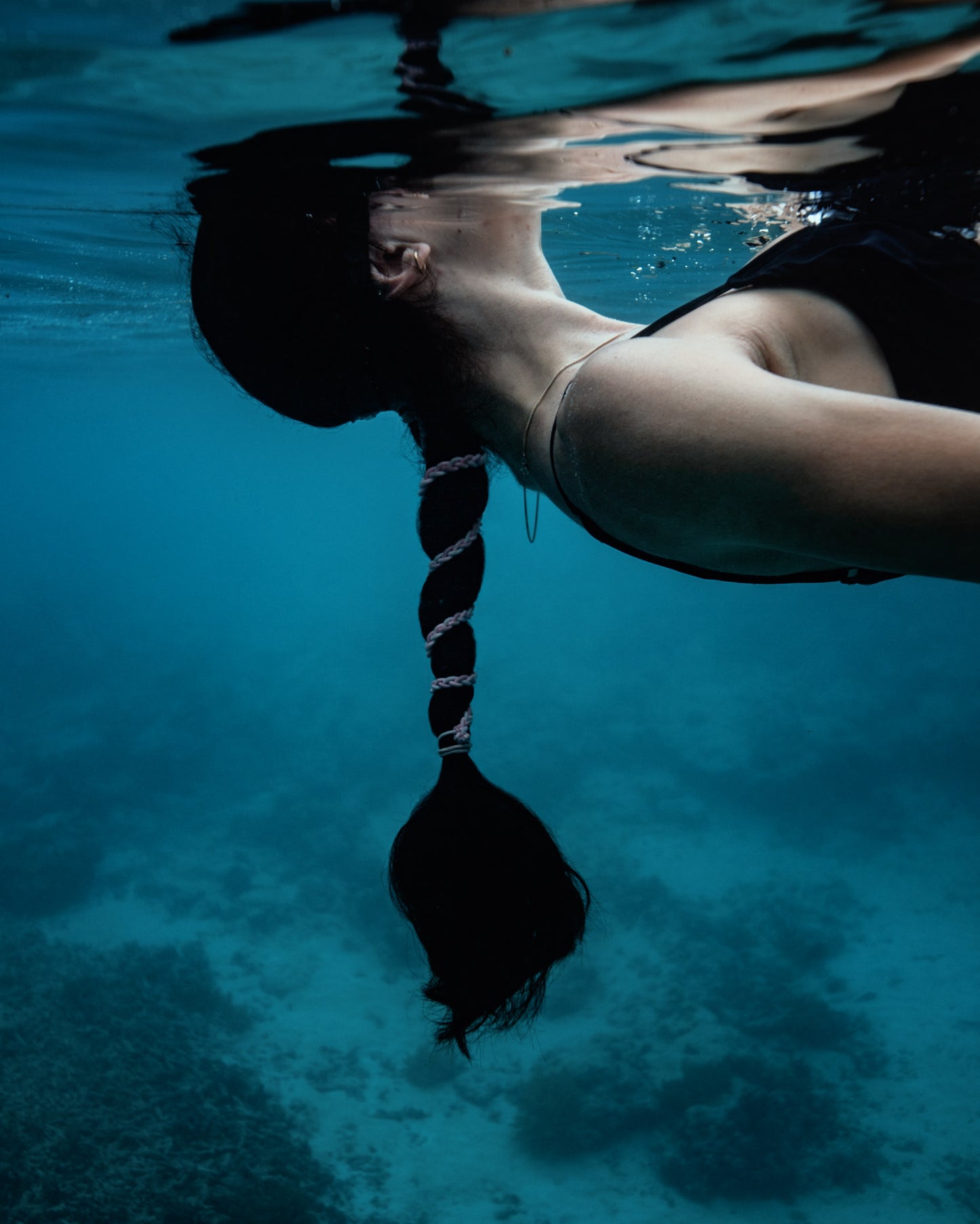 Girl with blue hair tie tied in hair underwater