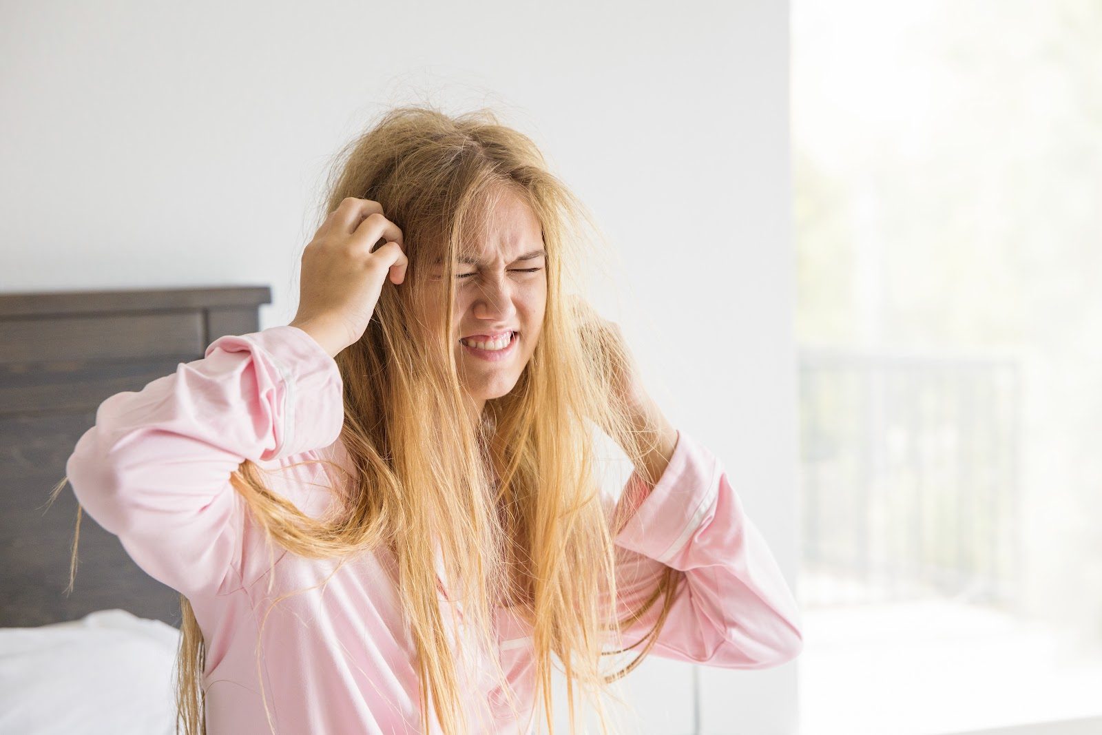 Frustrated girl waking up with tangled, knotted hair